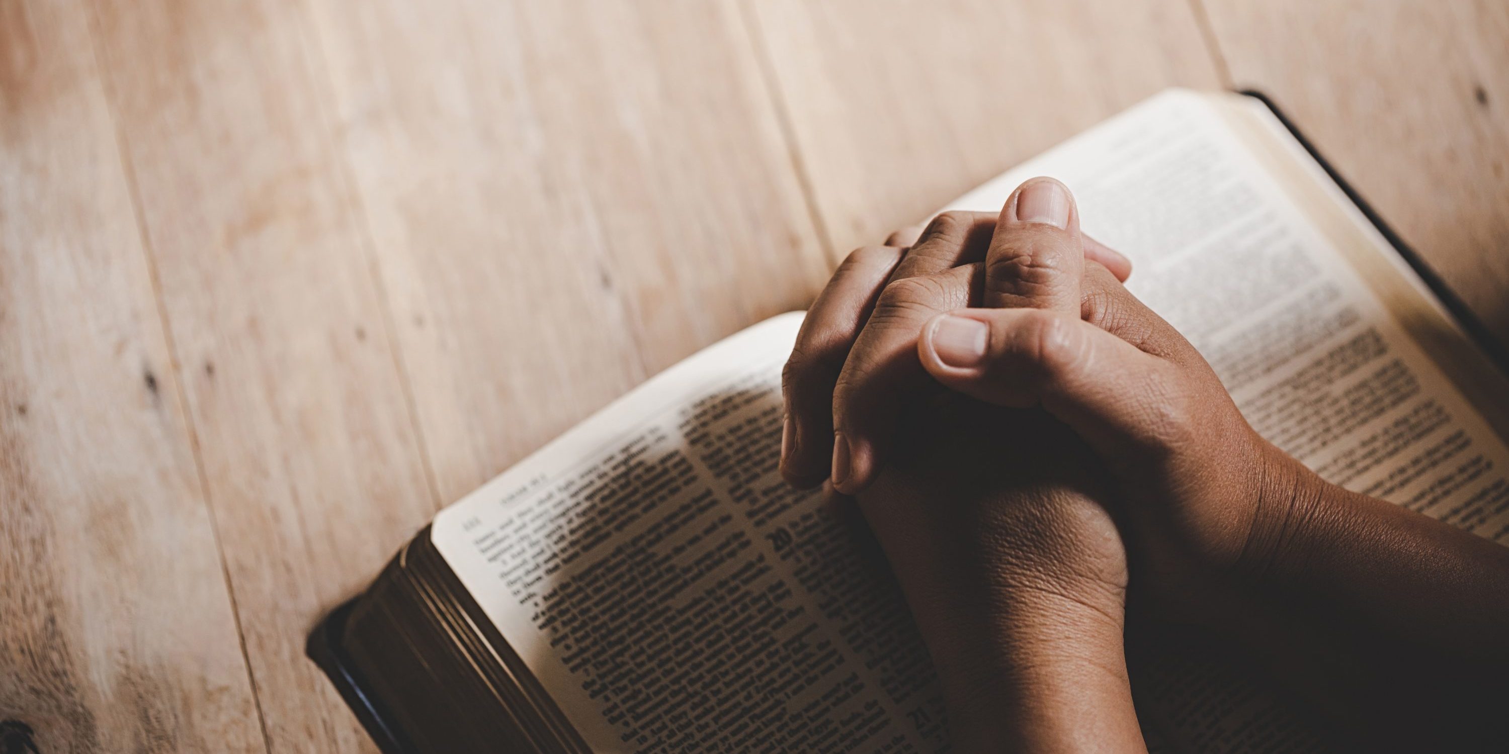 Spirituality and religion, Hands folded in prayer on a Holy Bible in church concept for faith.